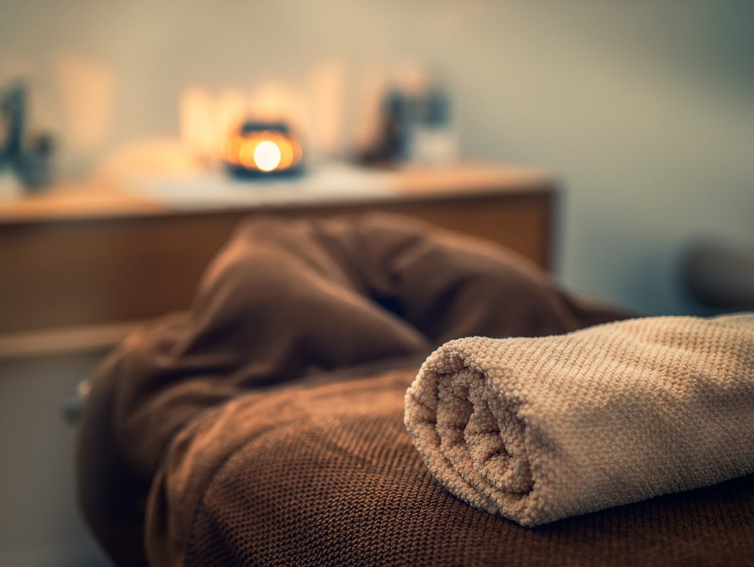 Massage Table with Towels and Lit Candle on a Cabinet